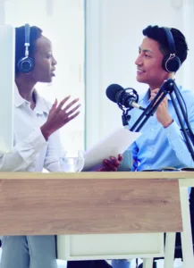 Two students wearing headphones speaking into a microphone