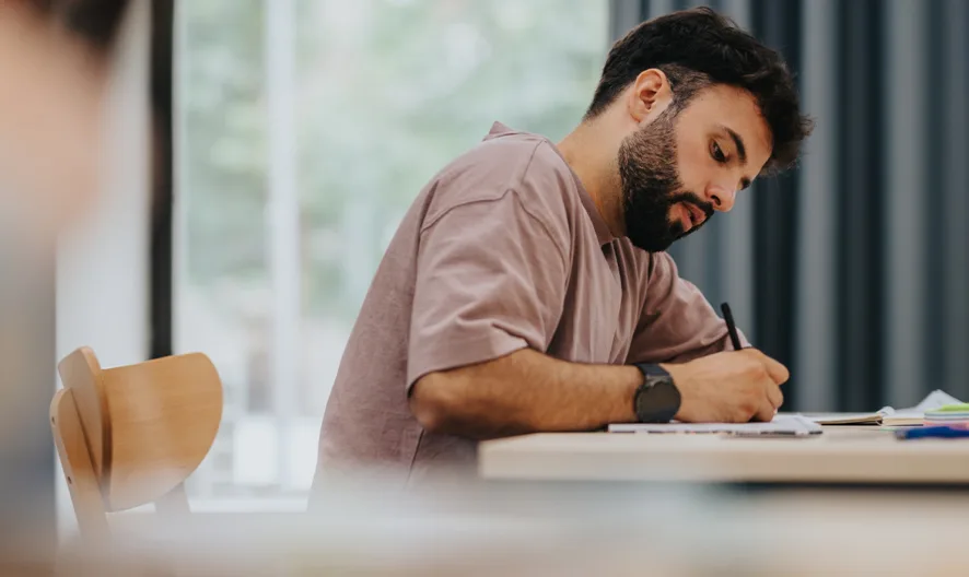 A student taking notes in a classroom setting.