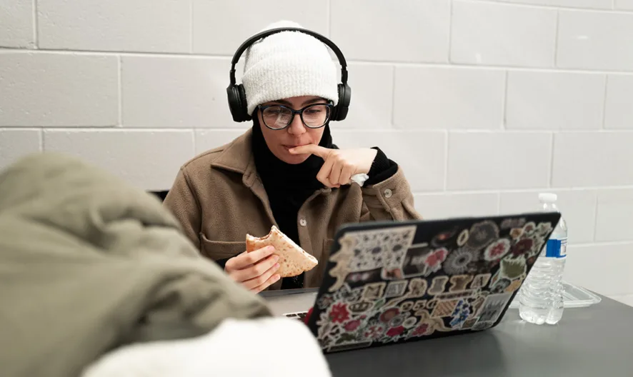 A woman wearing headphones and eating a sandwich.