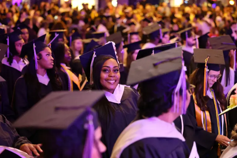 Graduate smile for picture at graduation ceremony