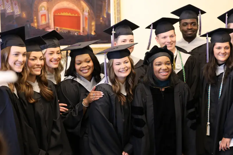 Graduates pose with faculty and staff at graduation ceremony